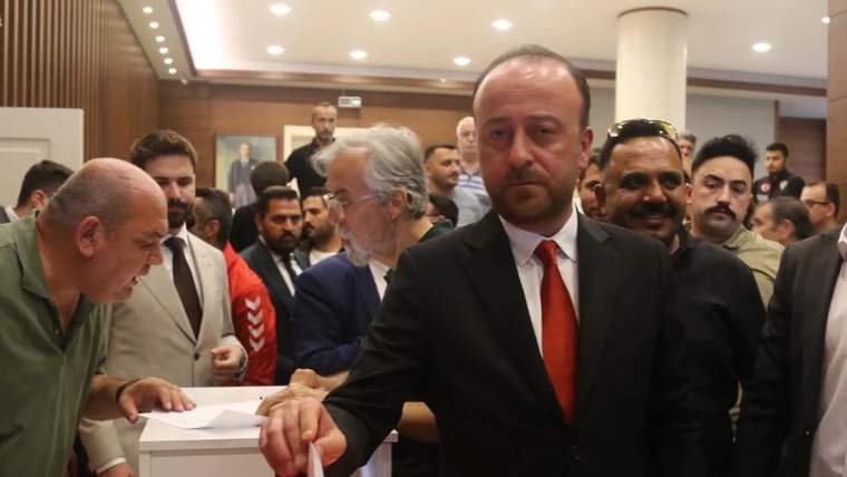 Kongrede oy kullanan bir adam, arka planda kalabalık bir grup yer alıyor.