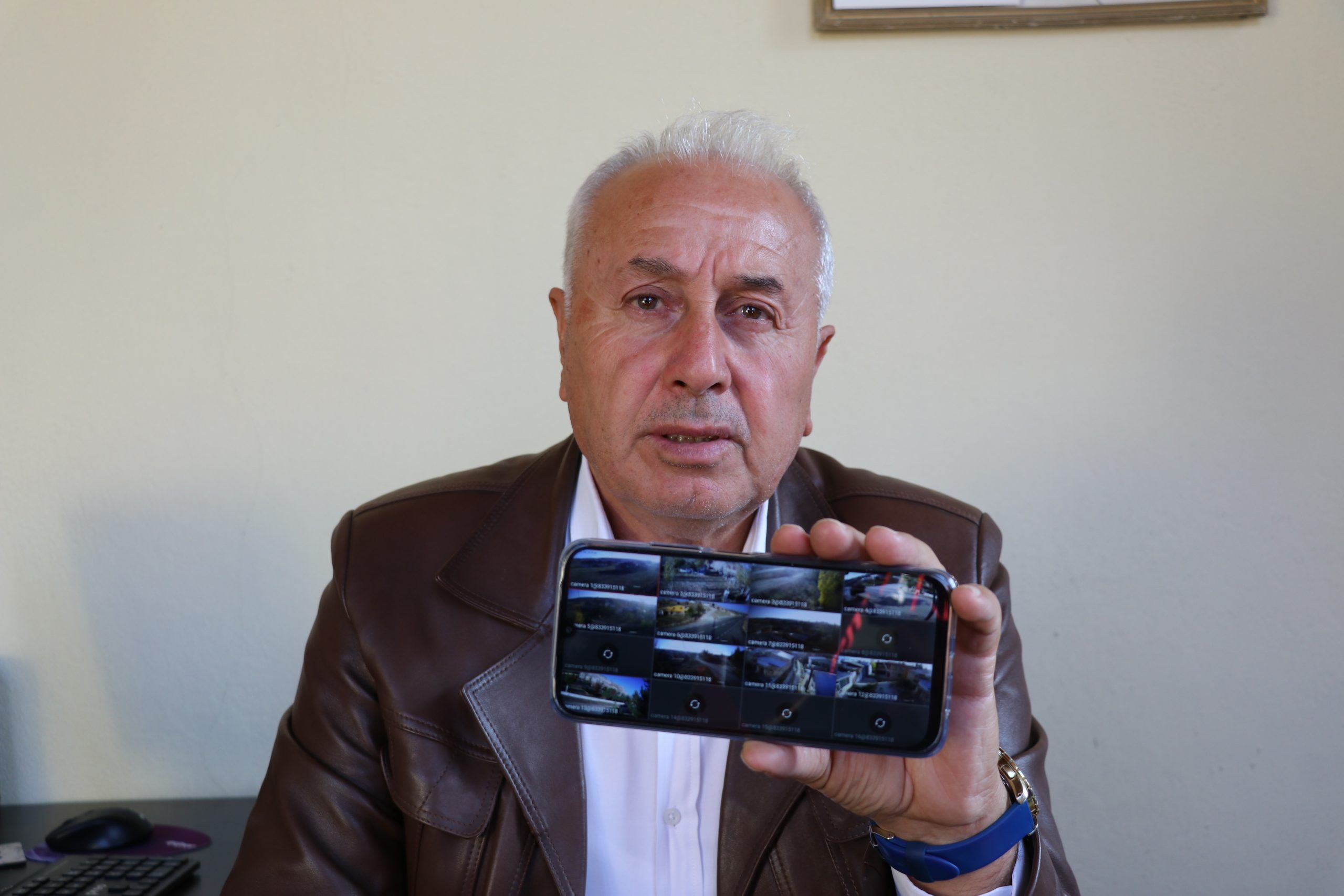 Bir kişi, akıllı telefonunda güvenlik kamerası görüntülerini gösteriyor.