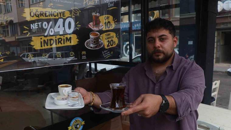 Bir kişi, kafenin önünde çay ve Türk kahvesi bulunan tepsiyi tutuyor; camda öğrenci indirimi yazısı görülüyor.