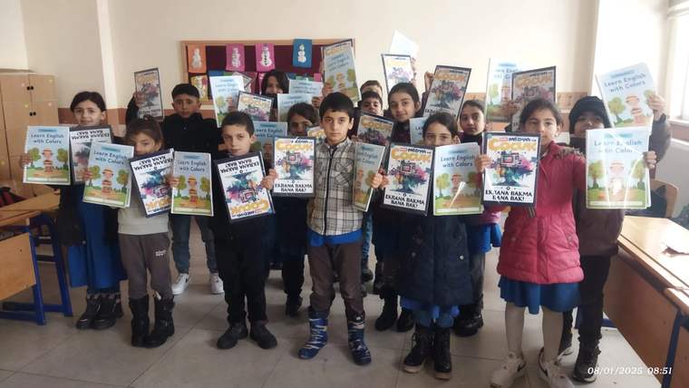 Bir grup çocuk, ellerinde çocuk dergileri ve kitaplarla bir sınıfta yan yana duruyor.
