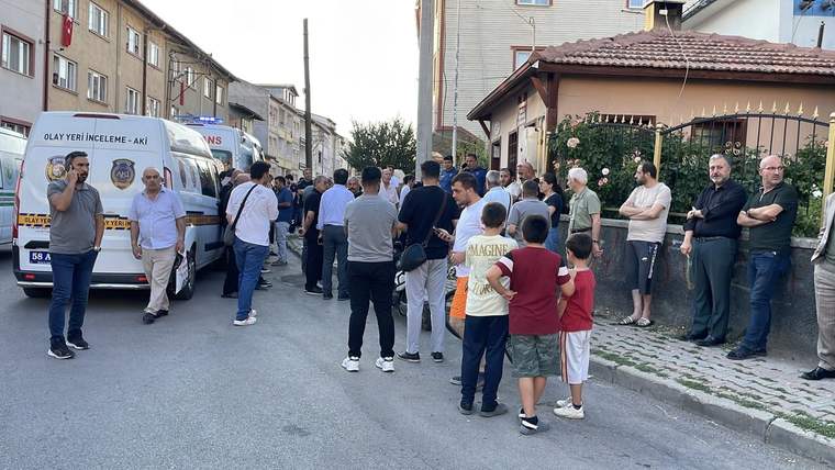 Muhtarlık binası önünde toplanmış kalabalık, ambulans ve polis aracı görünüyor.