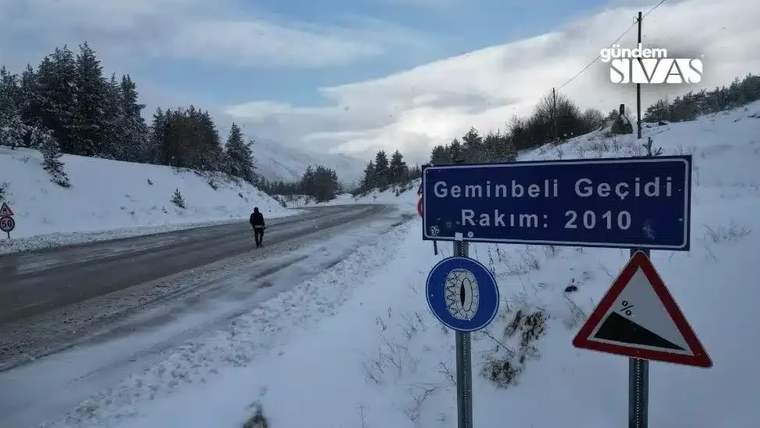 Geminbeli Geçidi tabelası, karla kaplı yolda bir kişi yürürken görünmekte.