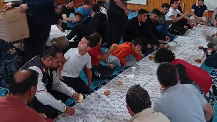 Sabah namazı sonrası bir grup insan, yerde oturarak birlikte yemek yiyor.