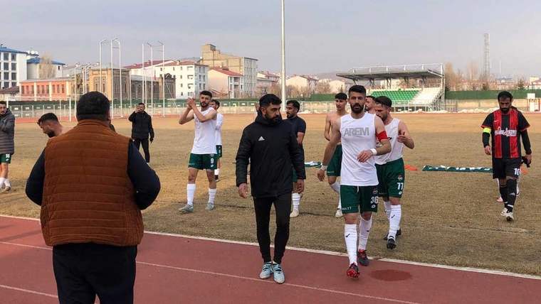 Futbolcular ve teknik ekip, saha kenarındaki atletizm pistinde yürürken görülüyor.