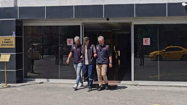“Sivas Emniyet Müdürlüğü” yazılı binanın girişinde üç kişi yan yana duruyor; camda sarı araç yansıması görülüyor.