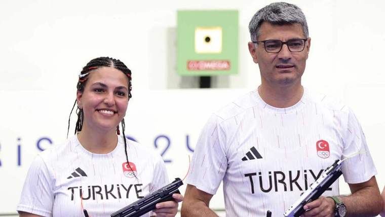 Altın madalya kazanan bir kadın ve bir erkek sporcu, gülümseyerek poz veriyor.
