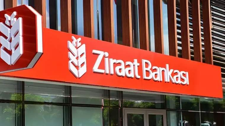 Kırmızı tabelasında Ziraat Bankası yazan banka şubesinin cam cepheli dış görünümü.