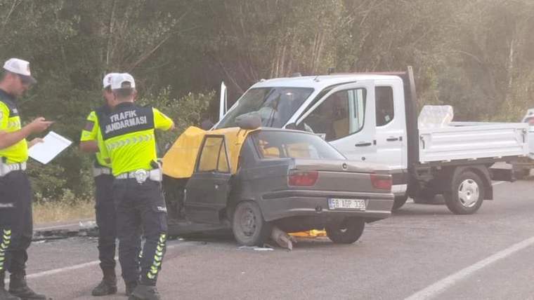 Yolda durdurulmuş bir otomobil ve yanında trafik polisleri, kazanın olduğu alanda inceleme yapıyorlar.