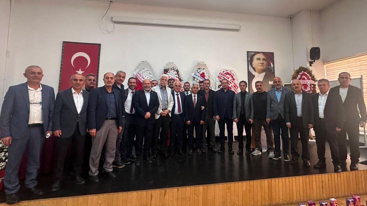 Salon içinde Türk bayrağı ve Atatürk portresi önünde yan yana duran kalabalık bir grup