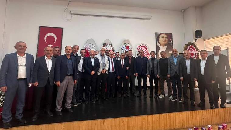 Salon içinde Türk bayrağı ve Atatürk portresi önünde yan yana duran kalabalık bir grup
