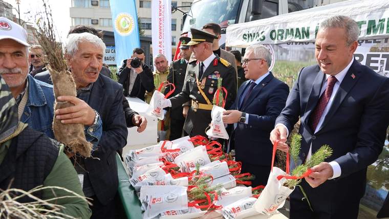 Fidan dağıtımı sırasında bir grup insan, poşetlerdeki fideleri tutuyor ve dağıtım yapıyor.