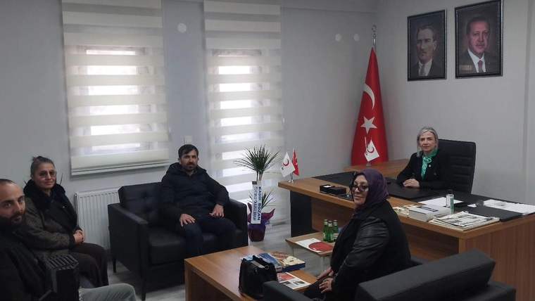 Kızılay Kars Şube Başkanlığı ofisinde dört kişi oturuyor, arka planda Türk bayrağı ve Atatürk portreleri var.