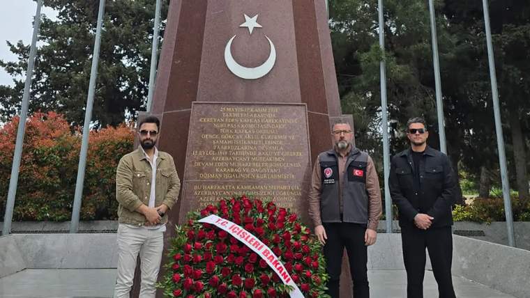 Türk bayrağı sembolü ve anıta çiçek bırakmış üç kişi, Bakü Türk Şehitliği'nde duruyor.