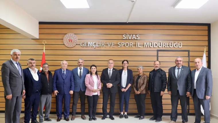 Sivas Gençlik ve Spor İl Müdürlüğü tabelası önünde, aralarında kadın ve erkeklerin bulunduğu bir grup poz veriyor.