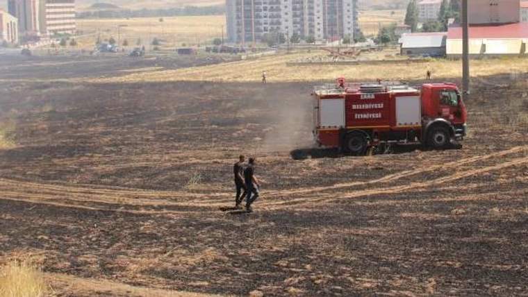 Kuru bir arazide, itfaiye aracı ve iki kişi yürürken görünüyor.