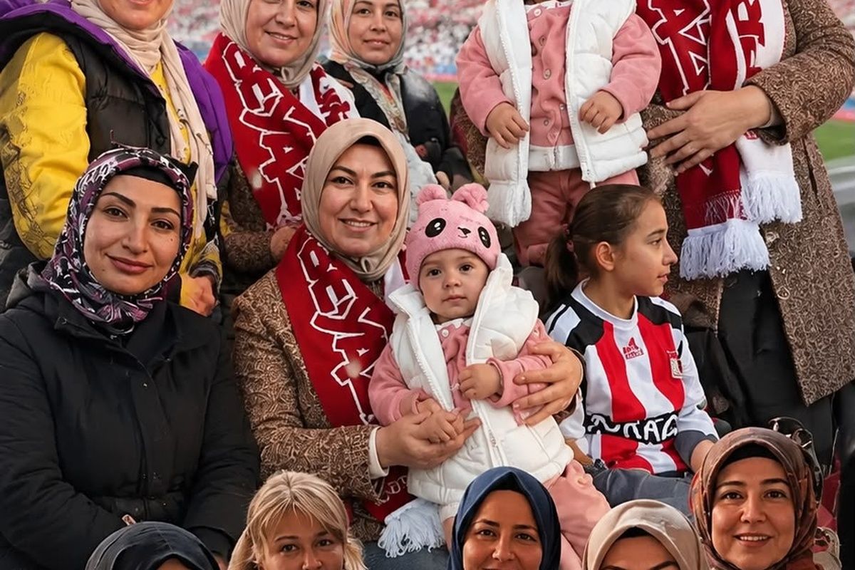 Kırmızı-beyaz atkılar takan kadınlar ve çocuklar, tribünde birlikte poz verirken görülüyor.