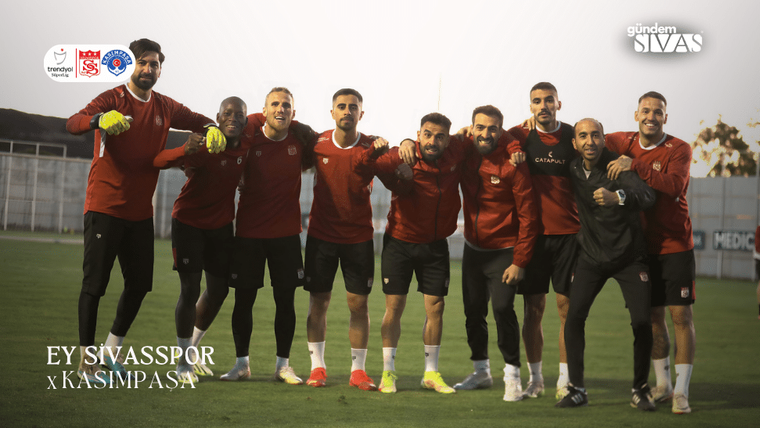 Kırmızı forma giymiş Sivasspor futbolcuları, antrenman sahasında gülümseyerek poz veriyor.