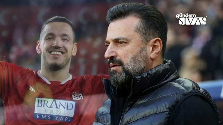 Siyah montlu sakallı bir adam önde dururken, arkasında kırmızı formalı gülen bir adam görülüyor.