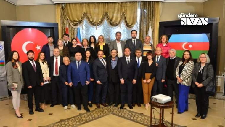 Türkiye ve Azerbaycan bayraklarının arkasında, bir grup insan poz veriyor.