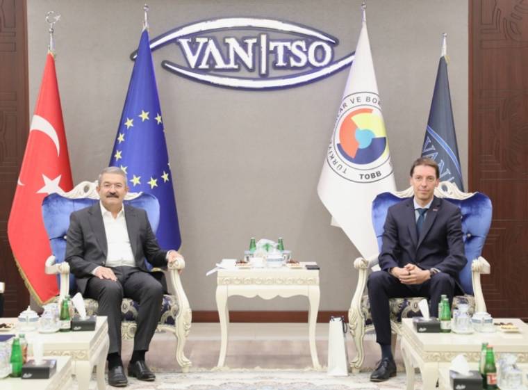 Duvarında VAN TSO yazılı amblem bulunan salonda iki kişi, Türk ve kurum flamaları arasında oturuyor.