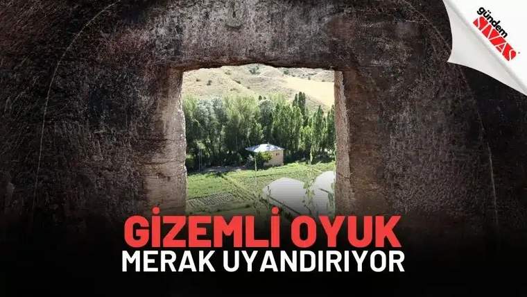 Büyük bir oyuk, çevresinde ağaçlar ve bir bina görünmekte.