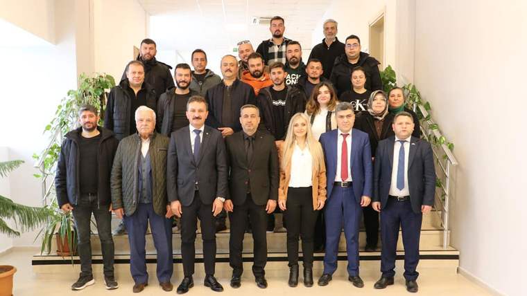 Merdivenlerde poz veren, aralarında takım elbiseli ve günlük giyimli kişilerin bulunduğu kalabalık grup