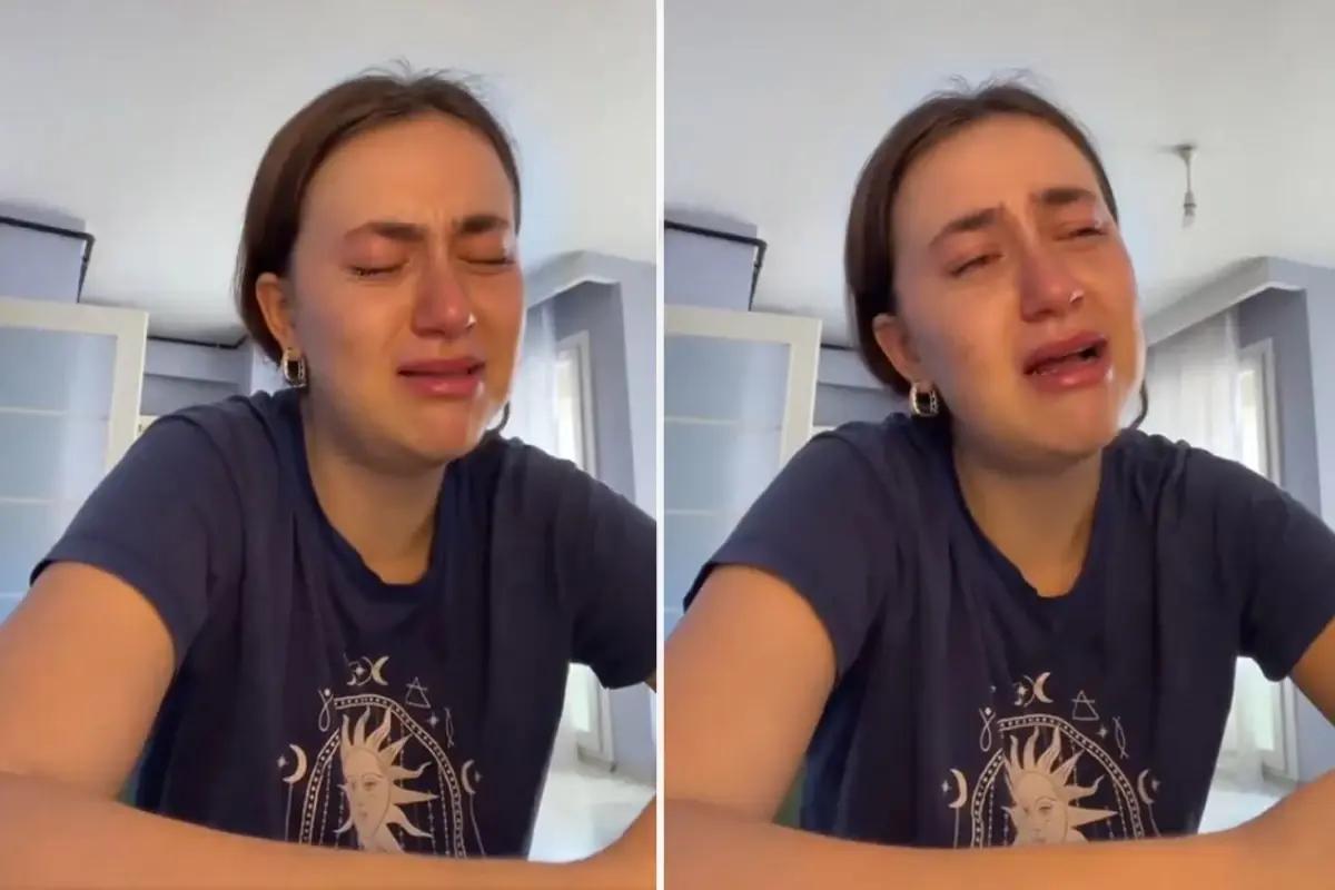 Gözyaşları içinde bir genç kadın, masanın üzerinde oturuyor ve üzgün görünüyor.