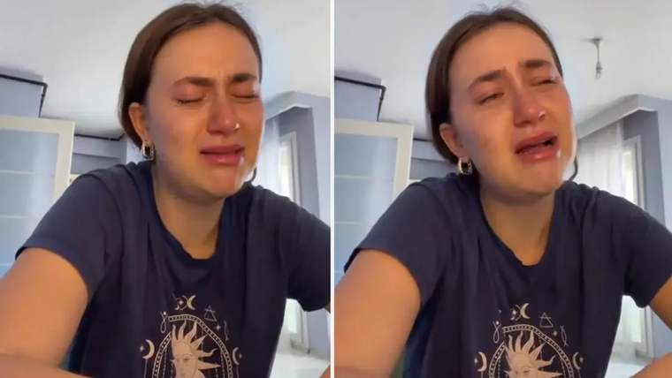 Gözyaşları içinde bir genç kadın, masanın üzerinde oturuyor ve üzgün görünüyor.