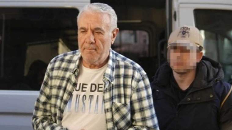 Beyaz saçlı yaşlı bir adam, yüzü bulanıklaştırılmış şapkalı bir kişiyle birlikte minibüs önünde görülüyor.