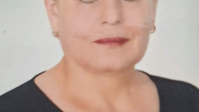 Bir kadının yüzü, kısa saçlı ve siyah bir bluz giymekte. Arka plan beyaz.