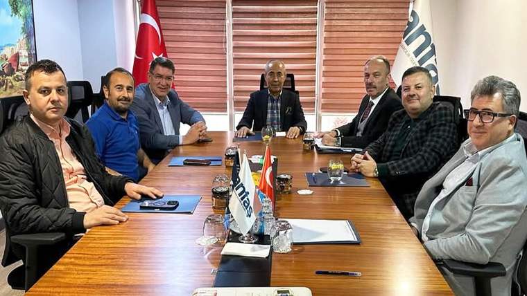 Toplantı masasında oturan yedi kişi, Türk bayrağı ve masa üzerindeki küçük flamalarla birlikte görülüyor.