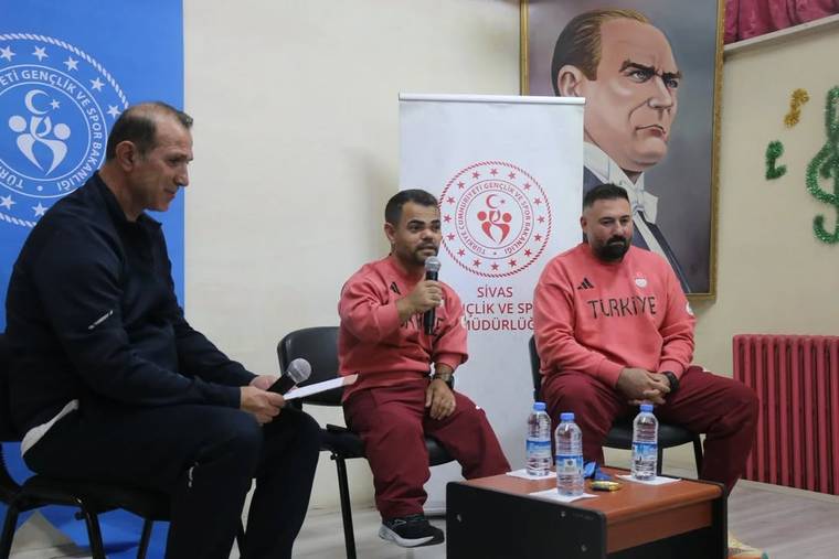 Gazi Paşa Ortaokulu'nda, Abdullah Kayapınar ve iki antrenör bir panelde konuşuyor.