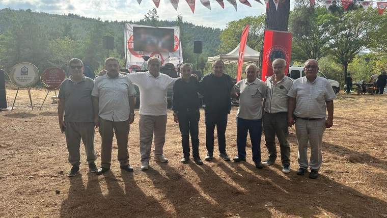 Bir grup erkek, açık alanda bir etkinlikte yan yana duruyor.