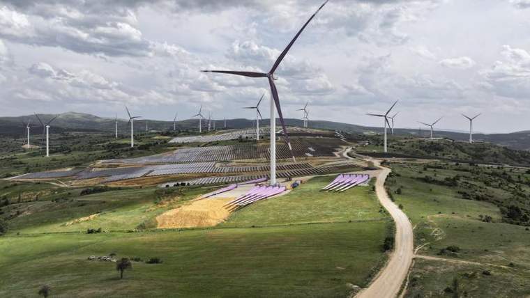Rüzgar türbinleri ve güneş panellerinin bulunduğu bir enerji santrali manzarası.