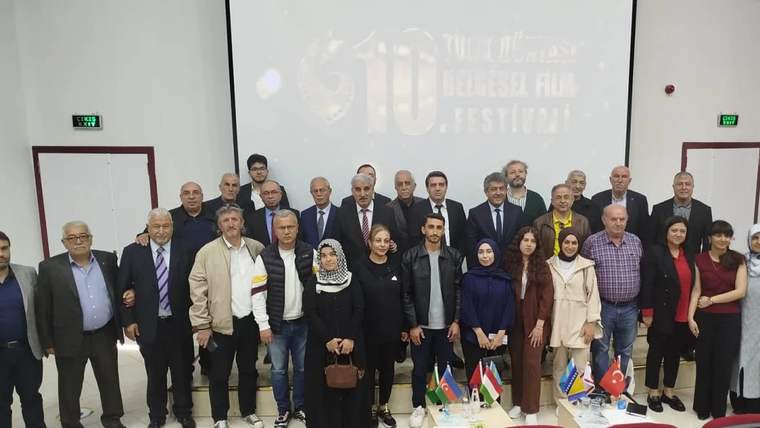 Fırat Üniversitesi'nde belgesel gösterimi için bir araya gelen katılımcılar, sahnede poz veriyor.