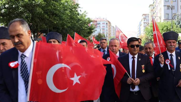 Türk bayrakları taşıyan kalabalık bir grup, yürüyüş yapıyor.