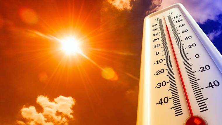 Parlak güneşin altında, kırmızı göstergesi yüksek sıcaklığı işaret eden bir termometre görülüyor.