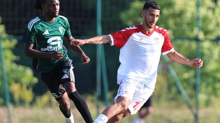 Beyaz forma giyen bir futbolcu, siyah forma giyen rakibine topu sürüyor.