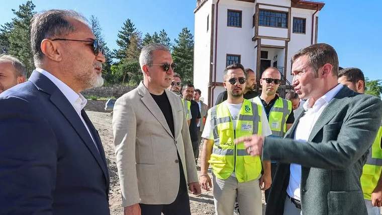 Tarihi kalede inceleme yapan kişiler, çevrede iş güvenliği ekipmanları giymiş çalışanlar var.