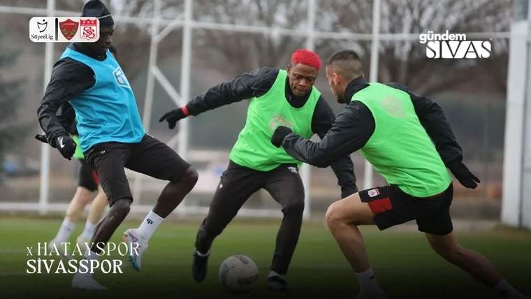 Antrenman yapan futbolcular, yeşil yelek giymiş ve top ile çalışıyorlar.