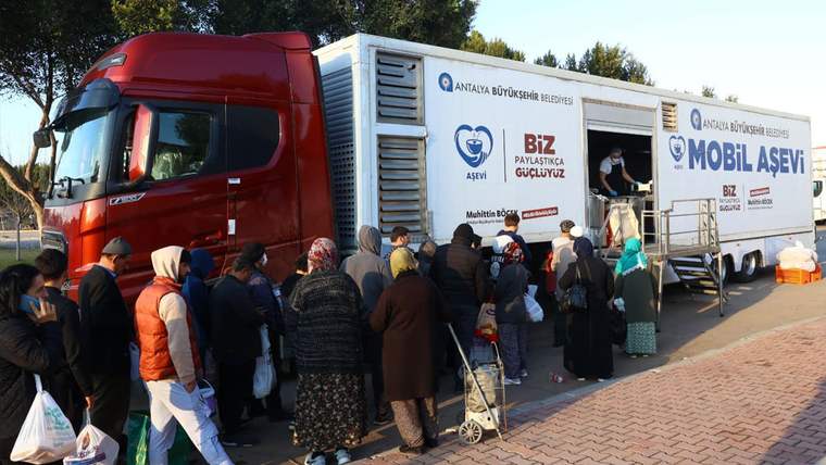 Antalya Büyükşehir Belediyesi yazılı mobil aşevi TIR'ının önünde yemek almak için bekleyen kalabalık