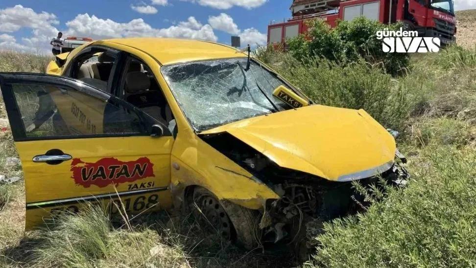 Yolda devrilmiş bir taksi aracı, etrafında yeşil bitki örtüsü var.