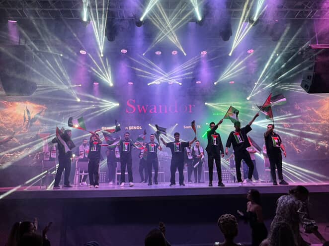 Filistin bayrakları tutan kuaförler, sahnede performans sergiliyor.