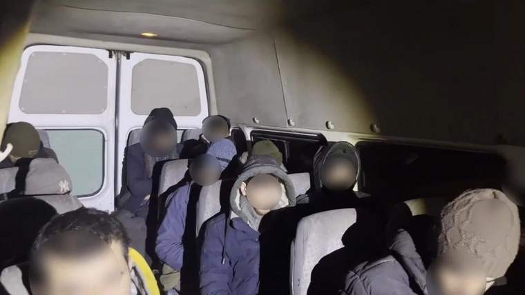 Minibüsün içinde, yüzleri bulanıklaştırılmış çok sayıda kişi koltuklarda oturuyor.