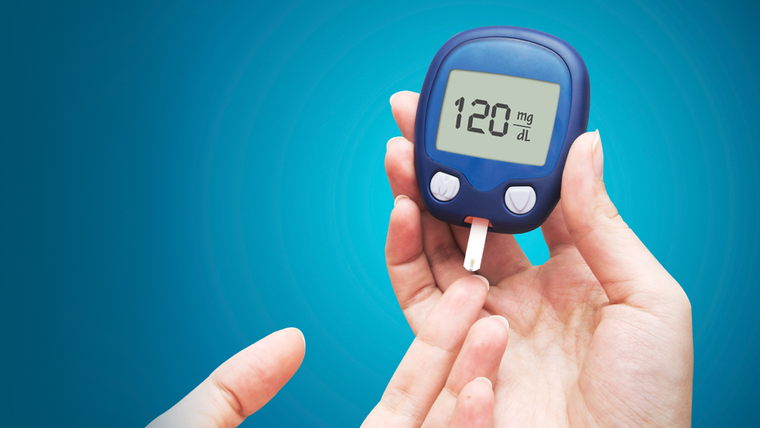 Bir el, kan şekeri ölçüm cihazının ekranında 120 mg/dL değerini gösteriyor.