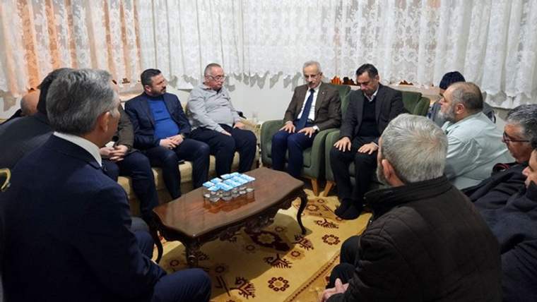 Bir grup erkek, bir odada oturmuş, taziye ziyaretinde bulunuyor.