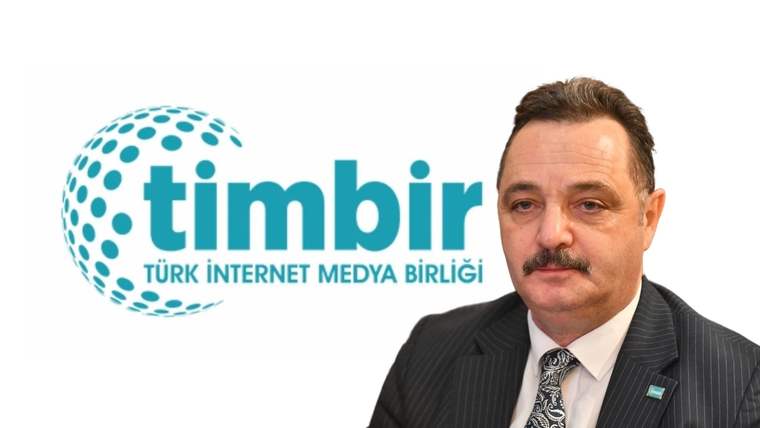 TİMBİR logosunun yanında bir kişi, takım elbise giymiş ve kameraya bakıyor.