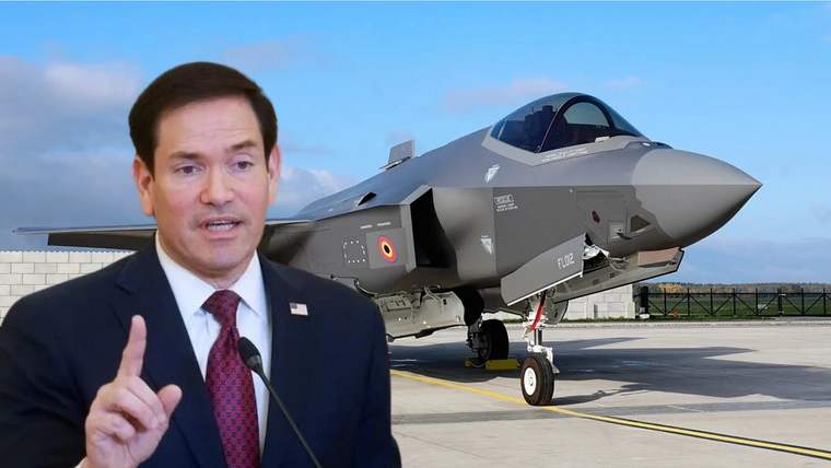 Mikrofon önünde parmağını kaldıran bir kişi ile arka planda duran F-35 savaş uçağı.