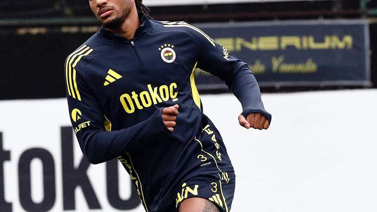 Fenerbahçe armalı antrenman kıyafeti giyen futbolcu, çim sahada koşu çalışması yapıyor.