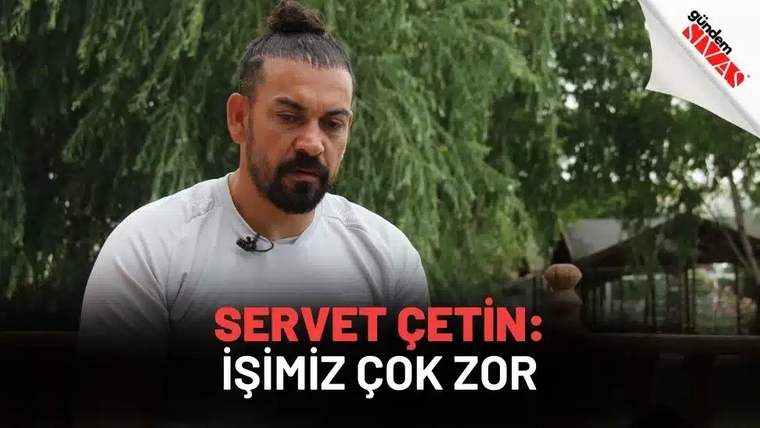 Bir kişi, açık havada otururken düşünceli bir şekilde kameraya bakıyor.